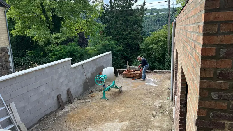 Chantier de rénovation en cours : mur en blocs béton monté au fond d'une cour